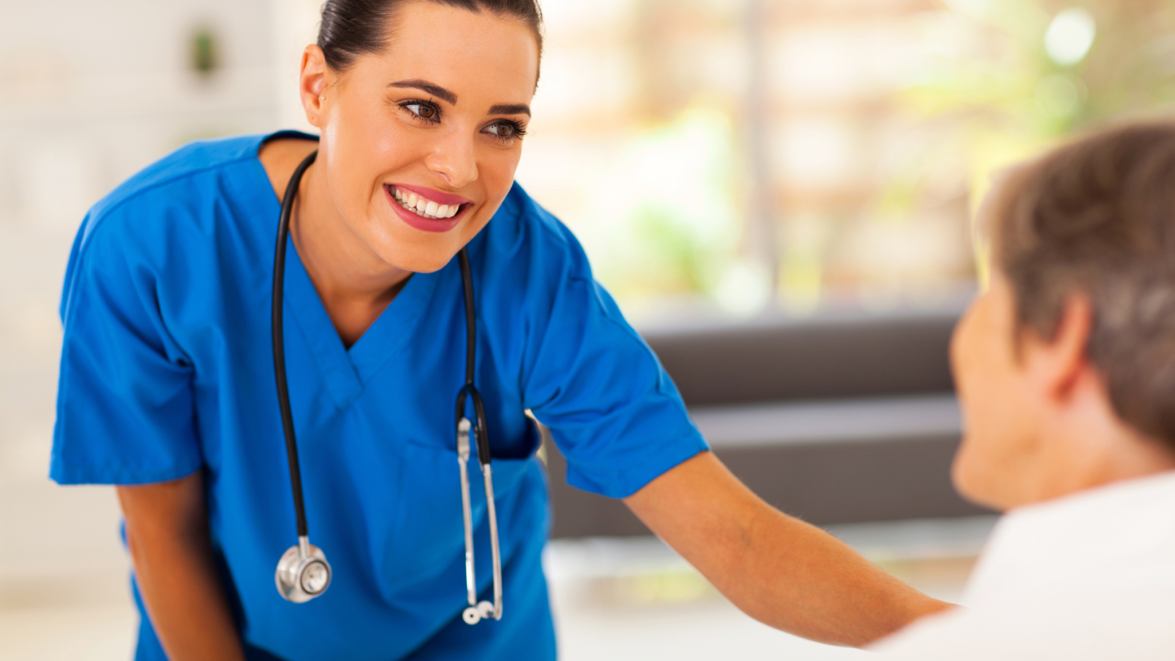 friendly young nurse talking to senior patient in hospital