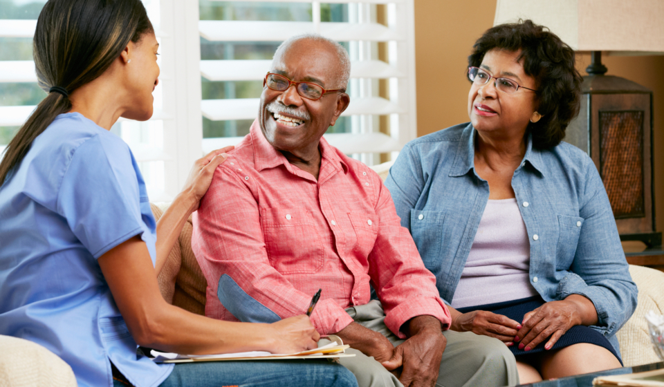 Nurse Making Notes During Home Visit With Senior Couple