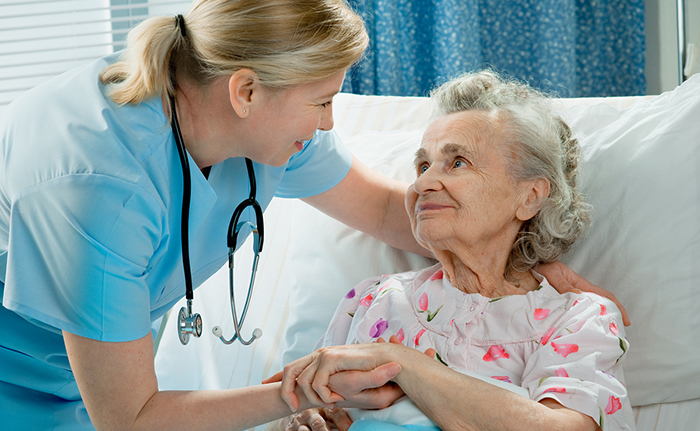 Nurse cares for a elderly woman lying in bed